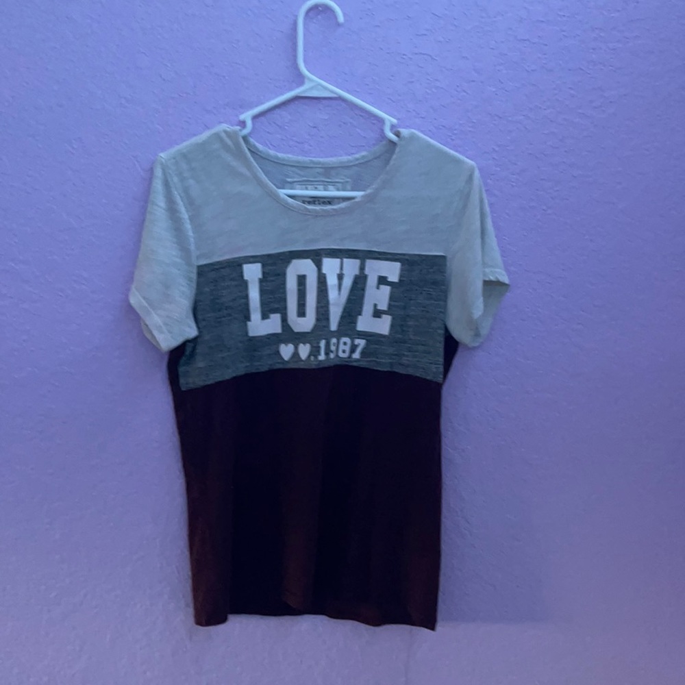 A maroon, gray, and white shirt and has written “ Love 🤍🤍. 1987”